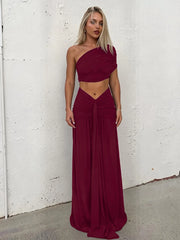 Model wearing a burgundy one-shoulder ruched crop top and maxi skirt