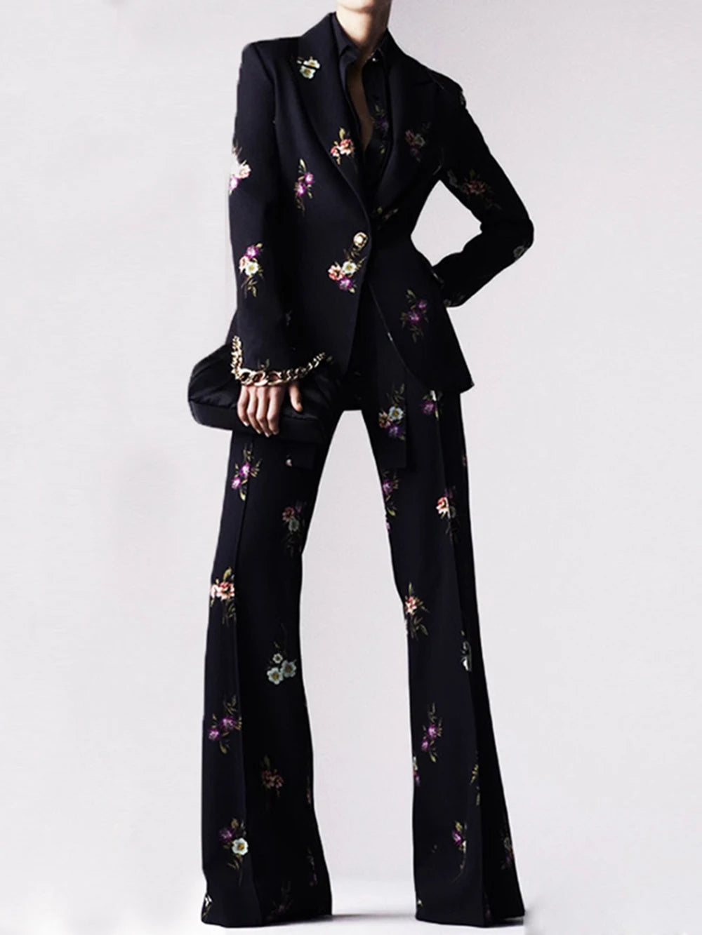 Model wearing a black floral print blazer and flare pants suit.