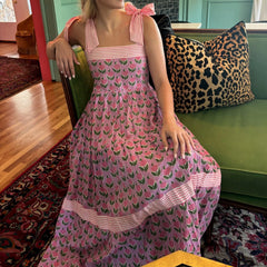 Woman in a pink dress with a floral pattern sitting on a green couch.