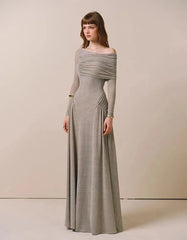 Woman wearing a long, off-shoulder gray dress against a plain background