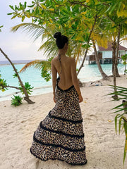 A model wearing a leopard print halter maxi dress with an open back, showcasing its glamorous style. Golden Atelier 1