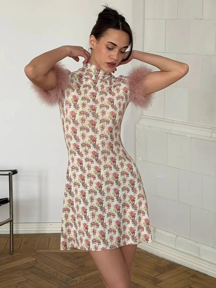 Woman wearing a floral dress with feathered sleeves in a room with white tiled walls.
