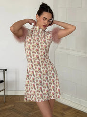 Woman wearing a floral dress with feathered sleeves in a room with white tiled walls.