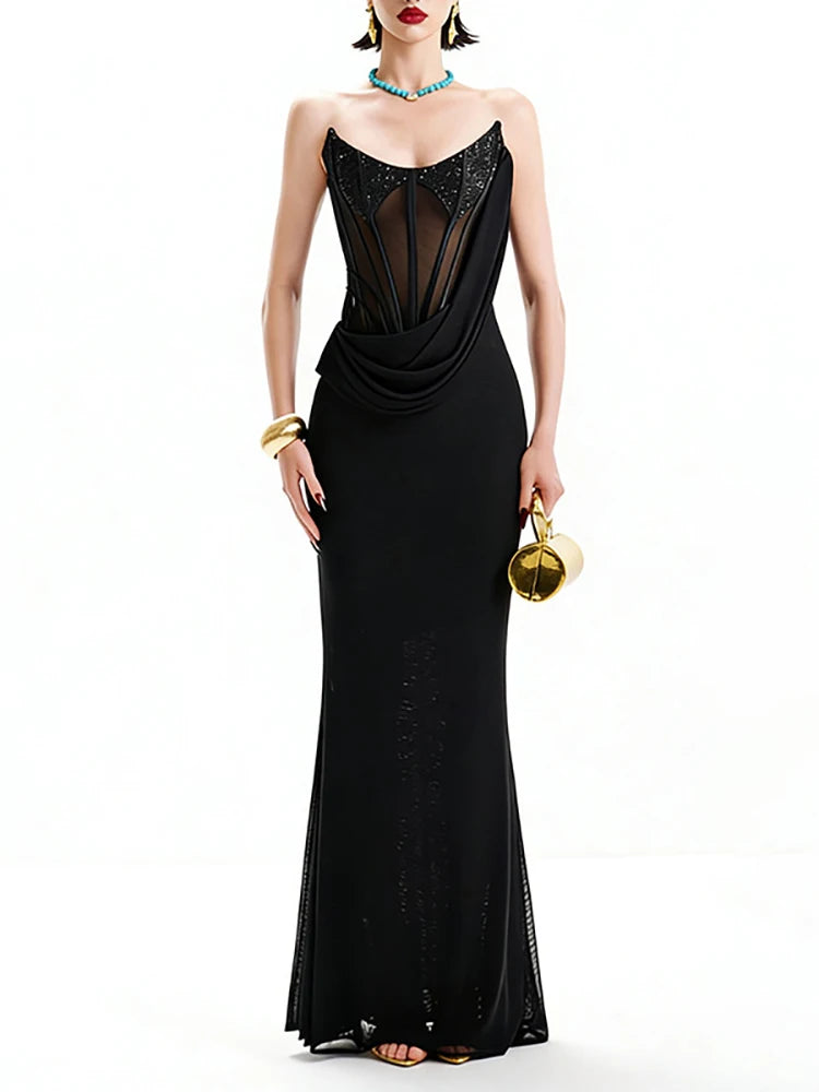 Woman wearing a black evening gown with sheer panels on a white background