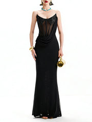 Woman wearing a black evening gown with sheer panels on a white background