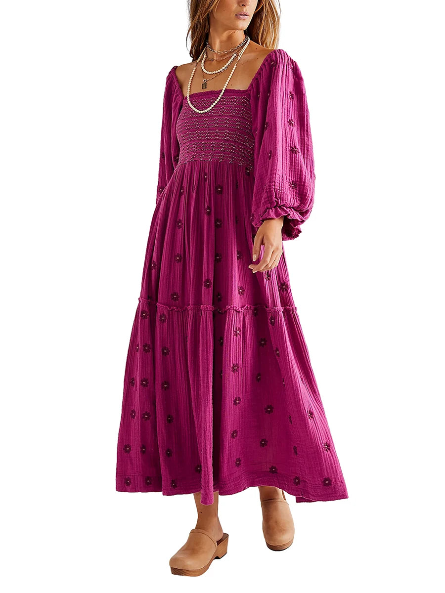 Woman wearing a long, magenta dress with black floral patterns on a white background