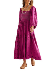 Woman wearing a long, magenta dress with black floral patterns on a white background
