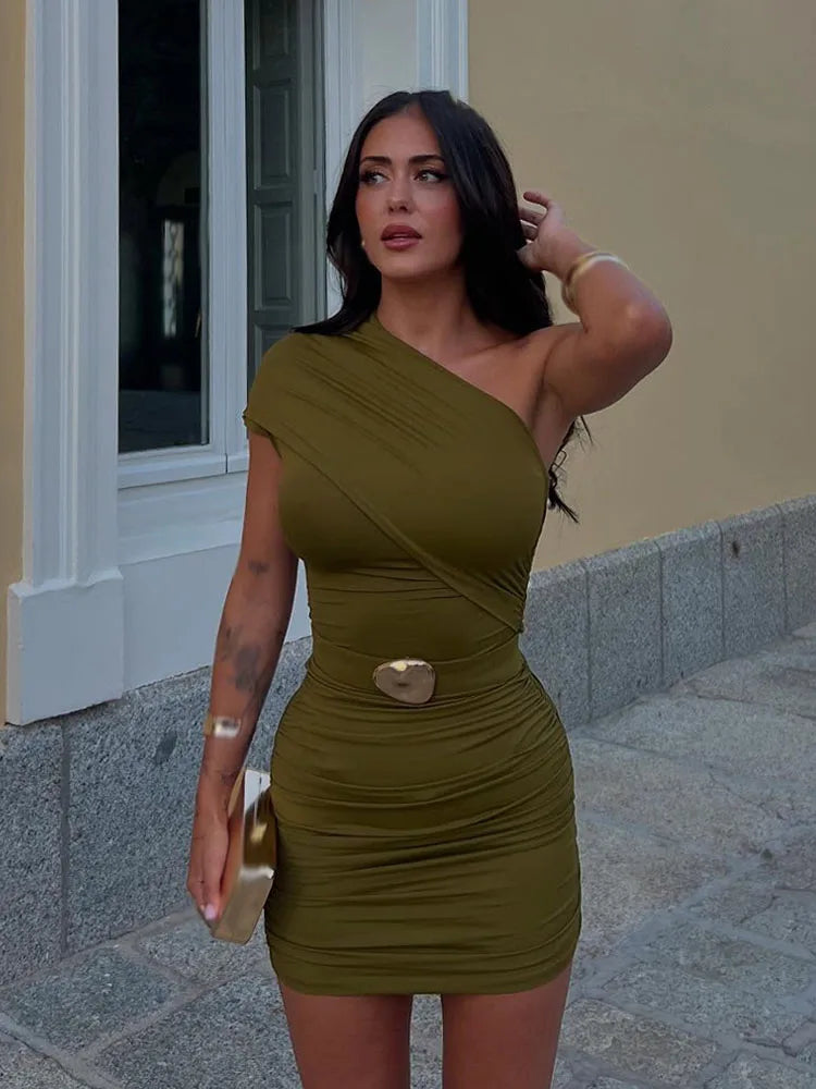 Woman wearing a green one-shoulder dress with a gold clutch in an urban setting.