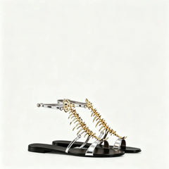 Pair of metallic silver and black flat sandals with gold fishbone embellishments