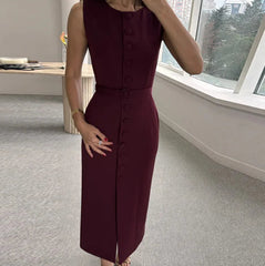 Woman wearing a burgundy dress with buttons in an indoor setting.