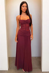 Woman wearing a burgundy evening gown against a plain background