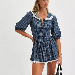 Woman wearing a navy polka dot dress with white lace trim on a white background