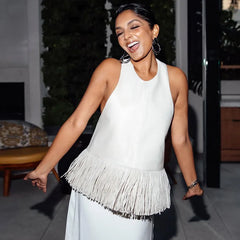Woman in a white sleeveless dress with fringe walking outdoors.