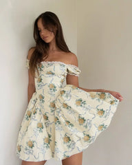 Woman wearing a floral off-shoulder dress against a plain background