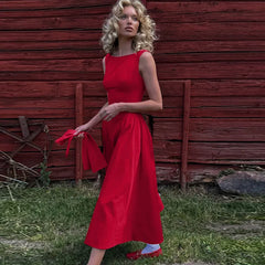 A woman wearing a Red sleeveless A-line midi dress, showcasing the straight neckline and flared skirt. 2