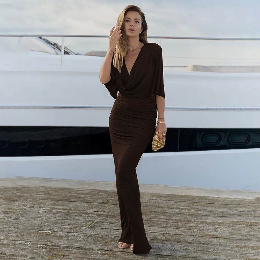 Woman in a brown dress standing on a dock with a yacht in the background