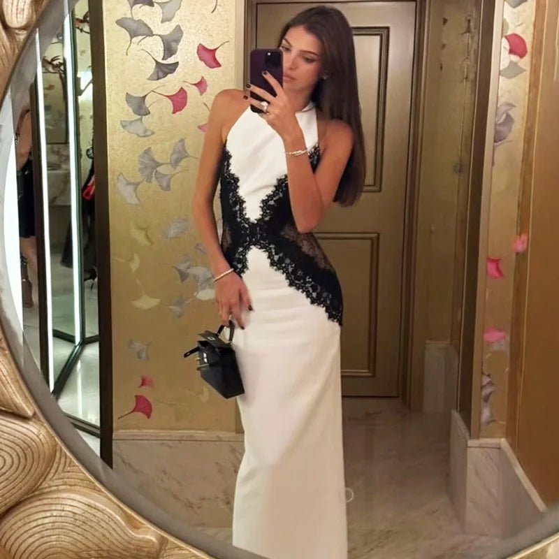 Woman taking a mirror selfie wearing a white and black dress.