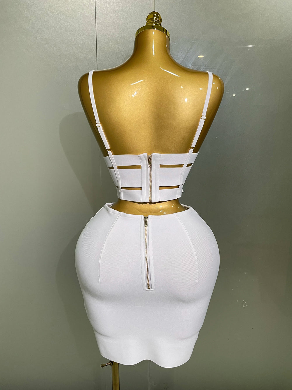 White dress with cut-out design on a mannequin against a plain background