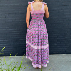 Person wearing a pink floral dress against a black brick wall.