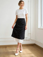 Model wearing a polka dot midi skirt with a white t-shirt and heels.
