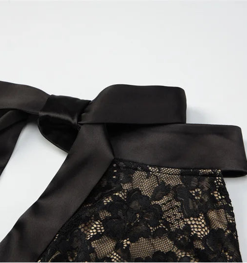 Black lace garment with a large bow on a white background