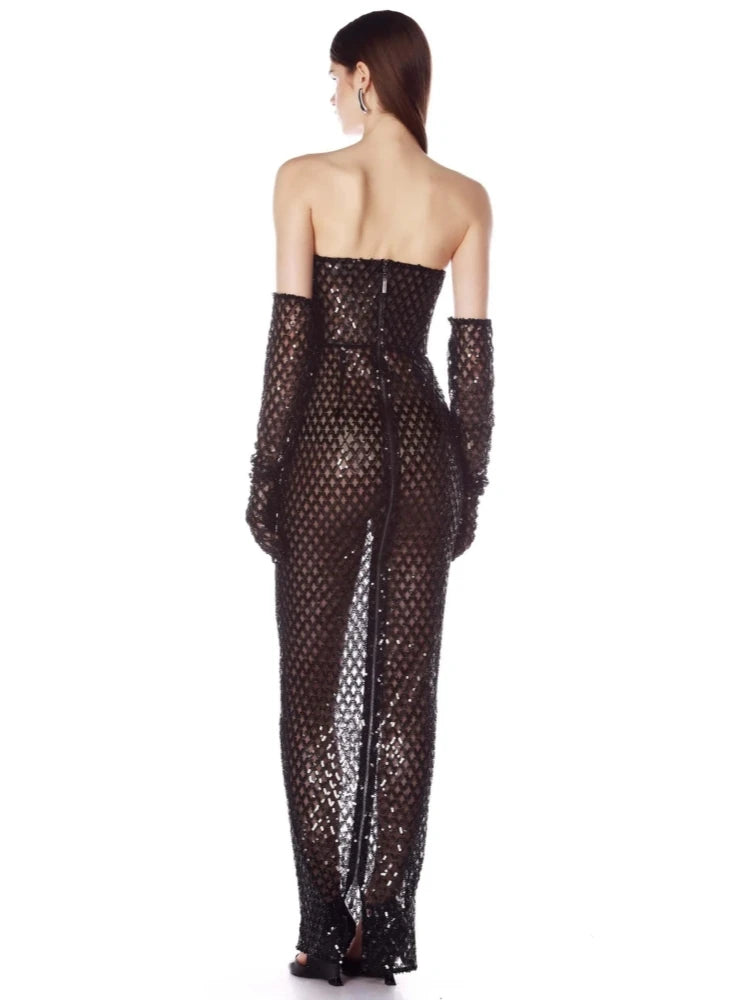 Woman wearing a black sequin strapless gown with matching gloves on a white background