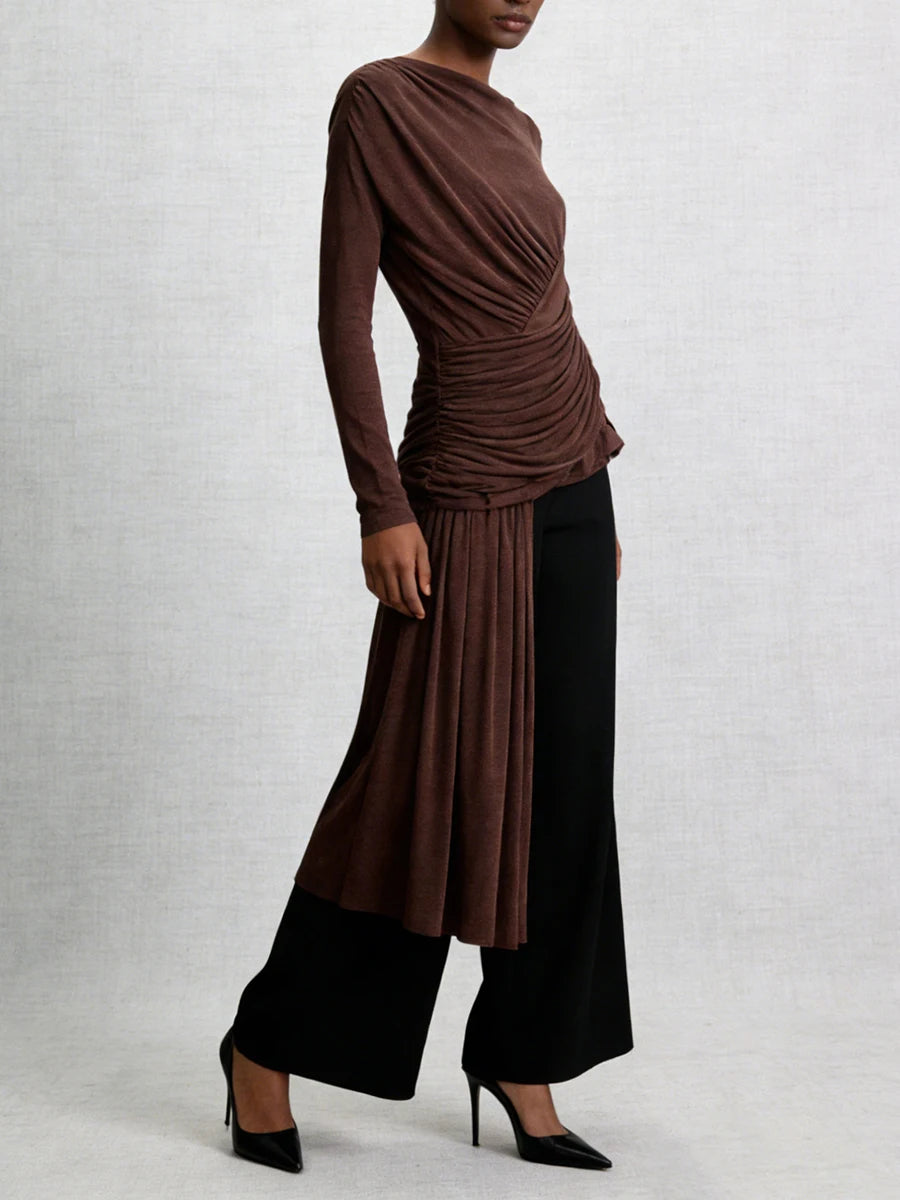 Woman wearing a brown top and black pants against a white background