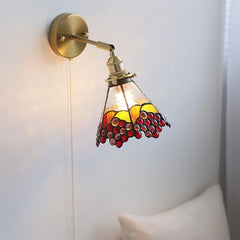 Wall-mounted lamp with stained glass shade featuring grapes on a white wall.