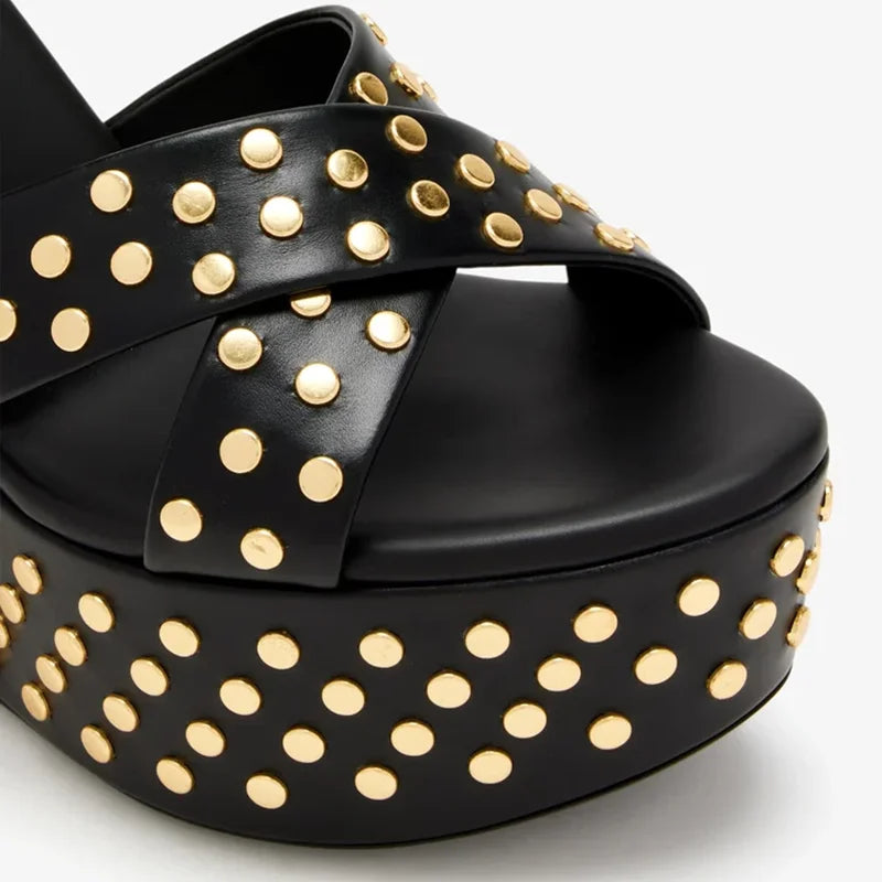 Close-up of the front straps and platform of a black leather wedge sandal with gold studs