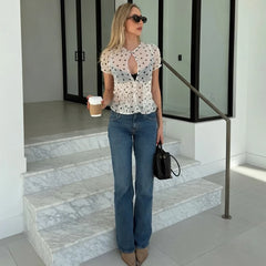 Woman wearing sheer polka dot puff sleeve blouse with coffee