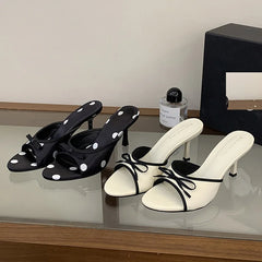 Pair of black polka dot heeled mules with a black bow
