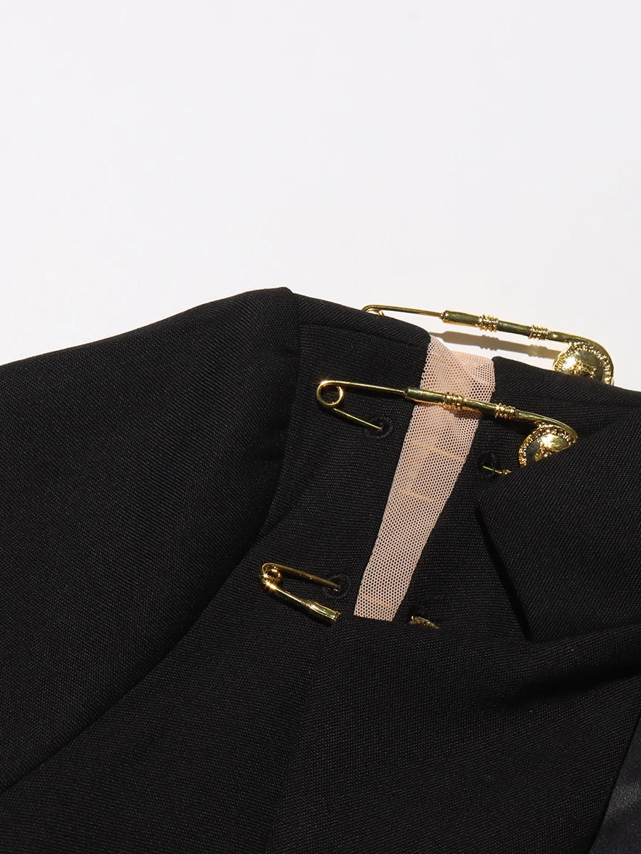 Black blazer with gold safety pins on a white background