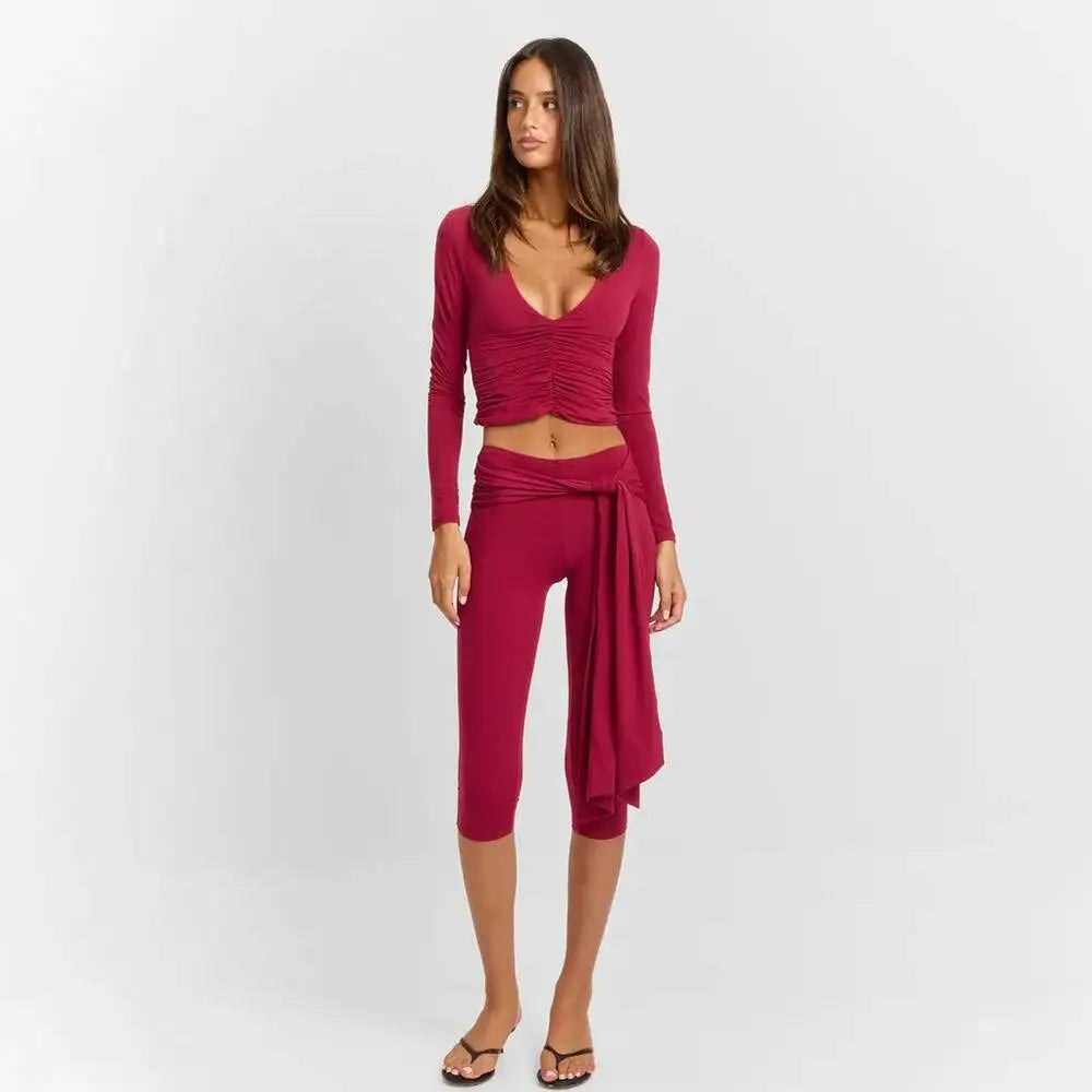 Model wearing a ruched v-neck long sleeve crop top and bandage capri pants set.