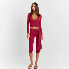 Model wearing a ruched v-neck long sleeve crop top and bandage capri pants set.