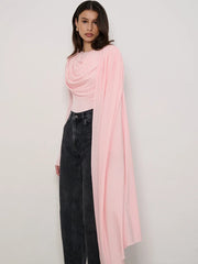 Woman wearing a pink top and black pants with a pink scarf on a white background
