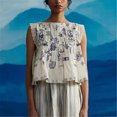 Woman wearing a floral off-shoulder top and striped pants against a blue mountain background