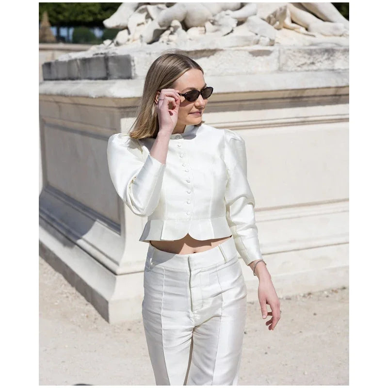 Woman in a white outfit standing in front of a classical building.