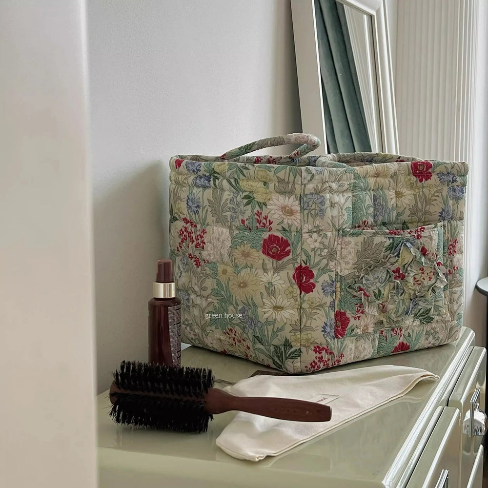 Floral-patterned bag on a dresser with a hairbrush and bottle of hair product.