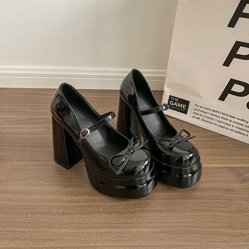Black platform shoes on a wooden floor with a white wall in the background.