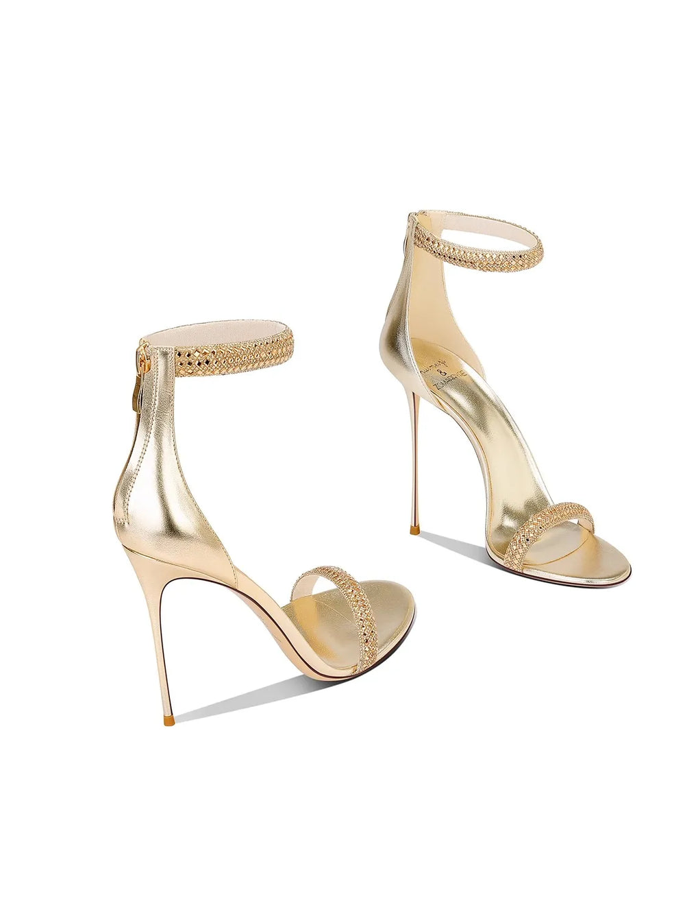 Gold high-heeled shoes with intricate designs on a white background