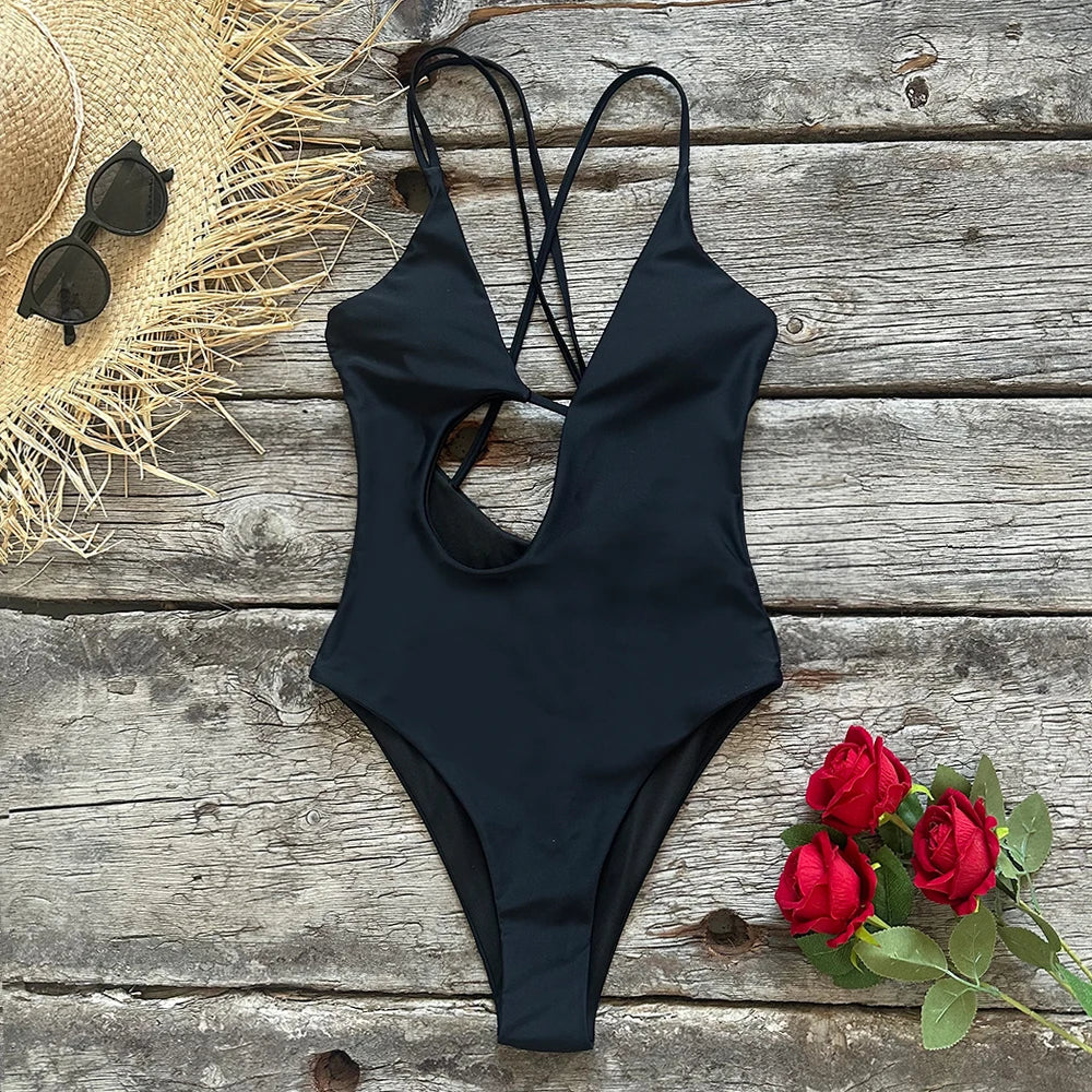 Flat lay of a black one-piece swimsuit with cut-out detail and halter straps.