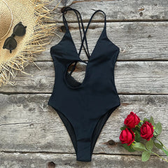 Flat lay of a black one-piece swimsuit with cut-out detail and halter straps.