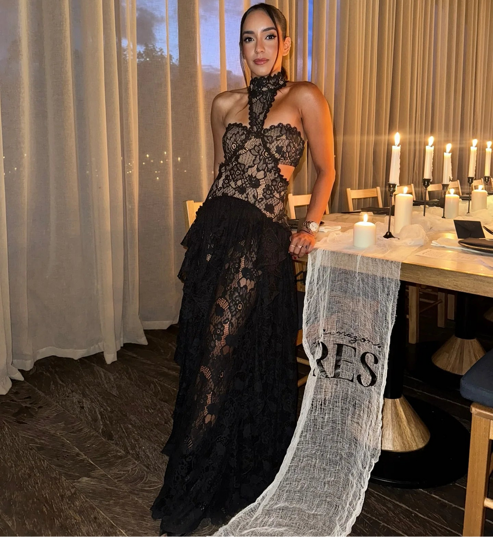 A woman in a black lace dress is standing in a restaurant.