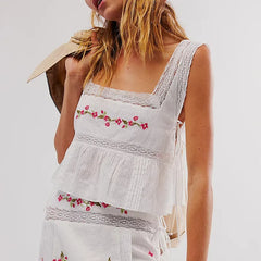 White embroidered dress with floral patterns on a plain background