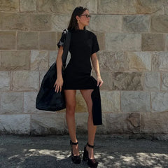 Woman in a black dress standing against a stone wall
