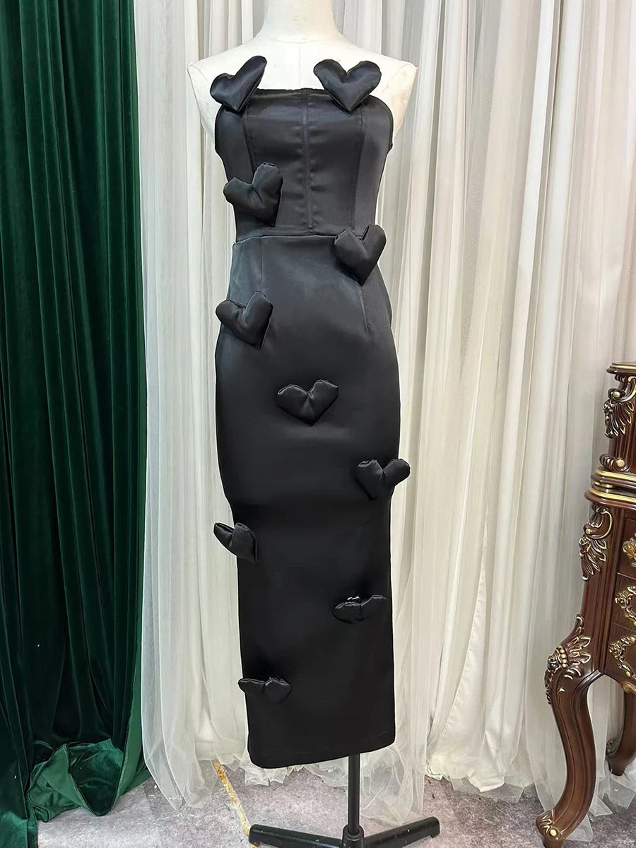 Black dress with heart-shaped cutouts on a mannequin against a white curtain background