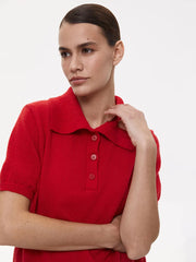 Woman wearing a red knitted polo shirt against a white background