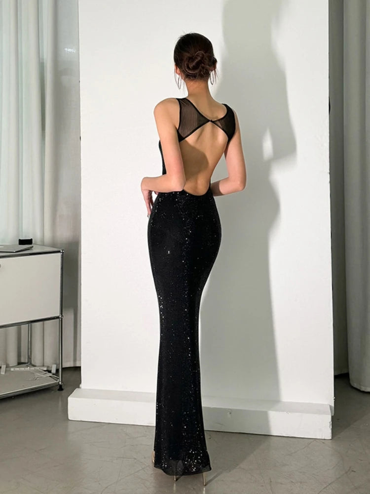 Woman wearing a black evening gown with open back in a minimal indoor setting
