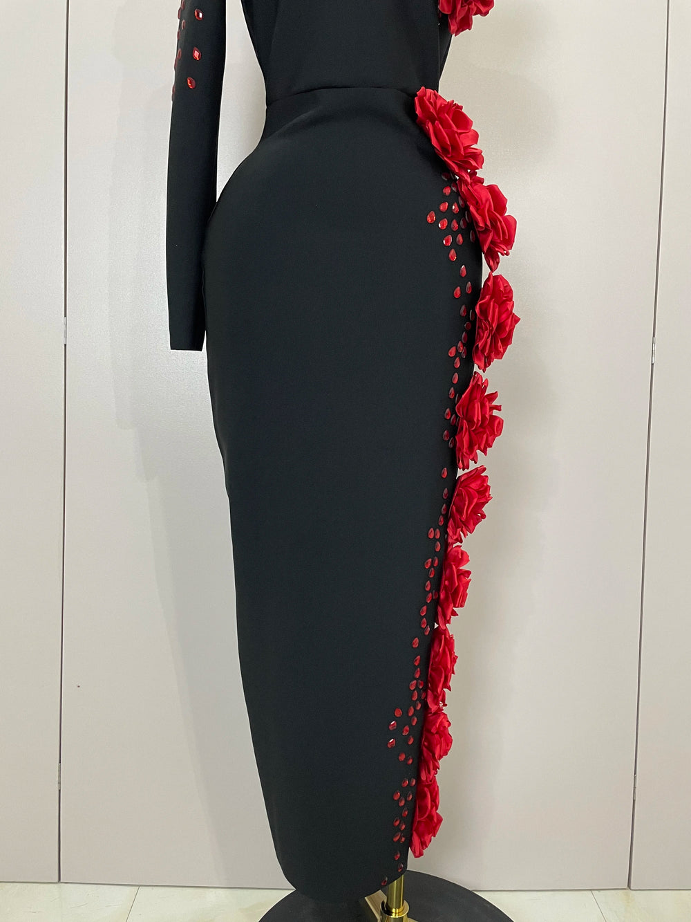 Black dress with red floral details on a mannequin against a white background