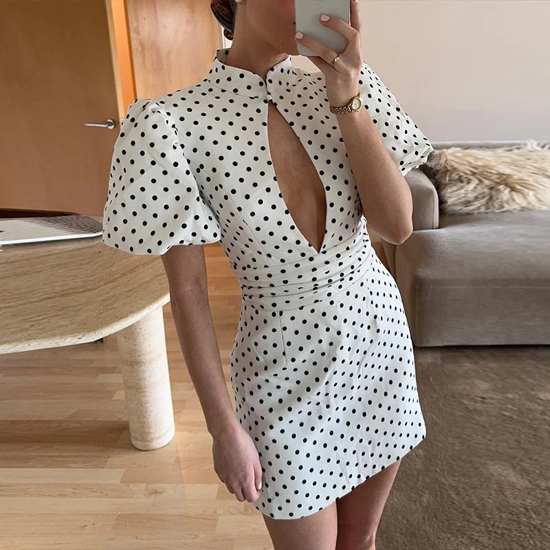 Person wearing a white dress with black polka dots in a living room setting.